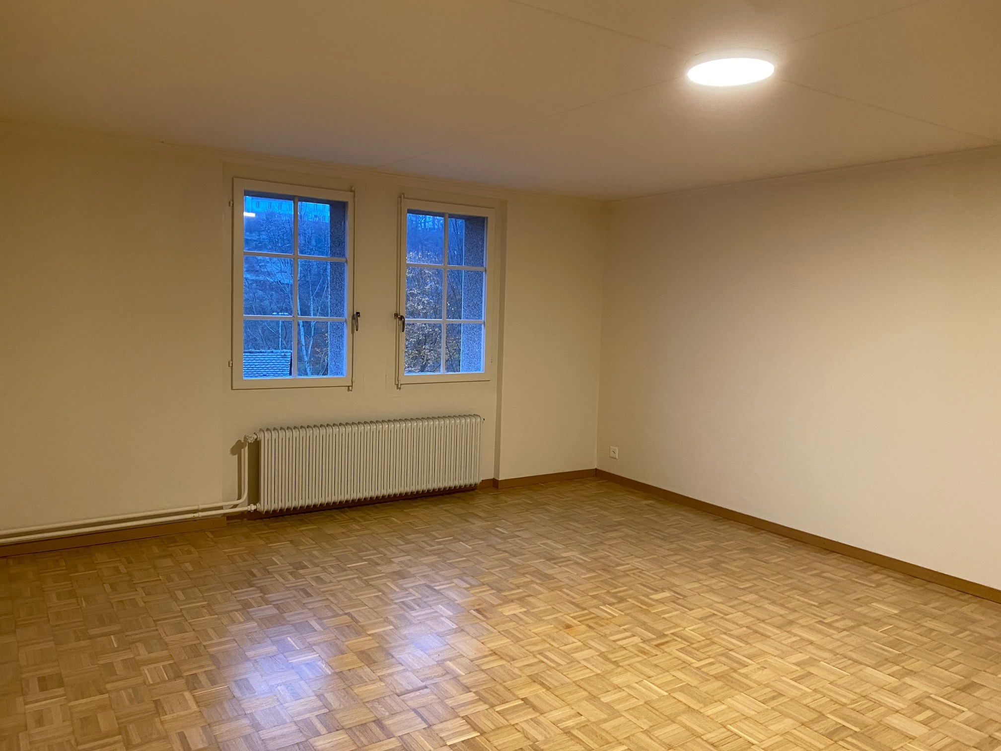 Leerer Raum mit zwei Fenstern und Heizkörper