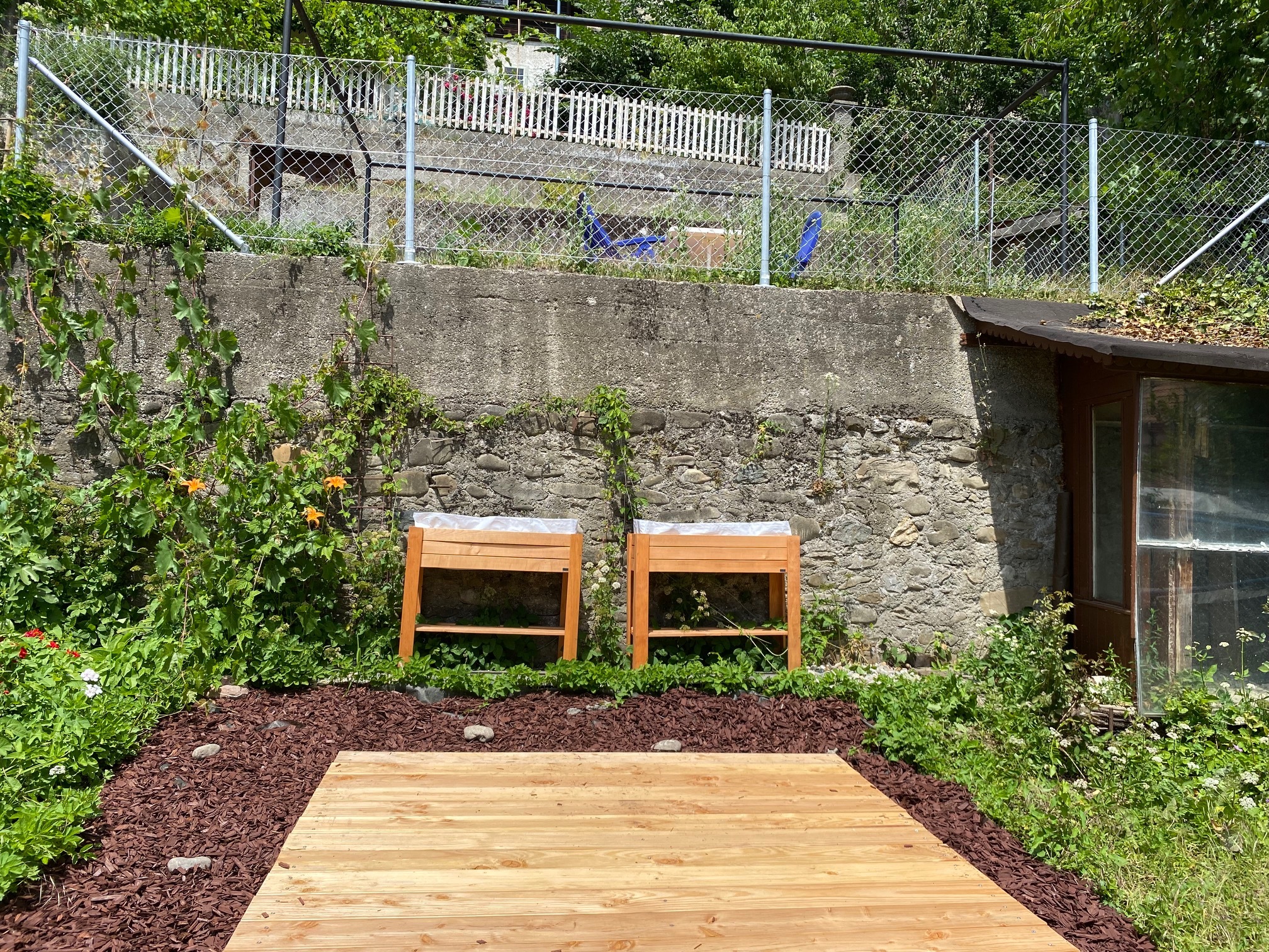 Gartenbereich mit Steinmauer und Holzpodest