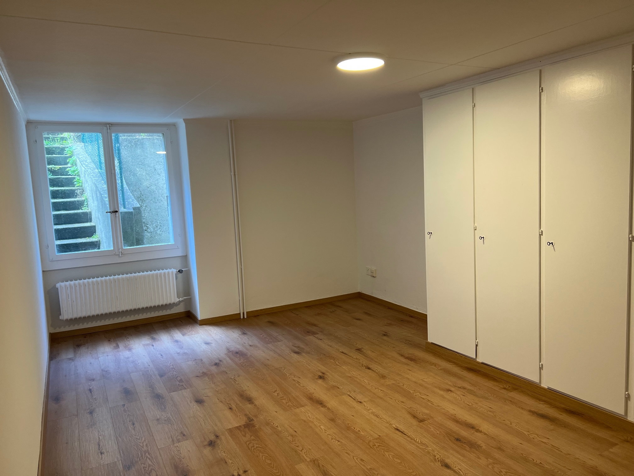 Helles, leeres Zimmer mit Dachschräge und Einbauschrank