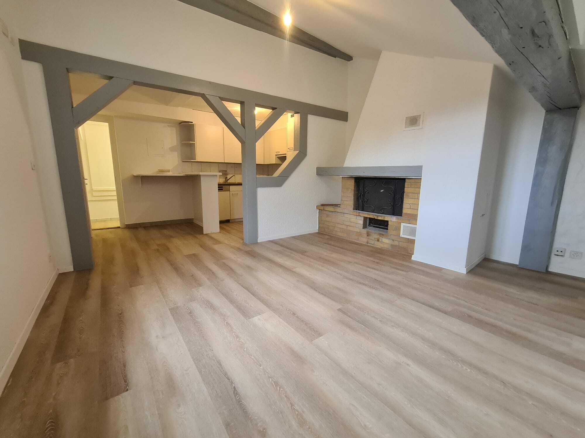 Offener Wohnraum mit Kamin und Durchgang zur Küche