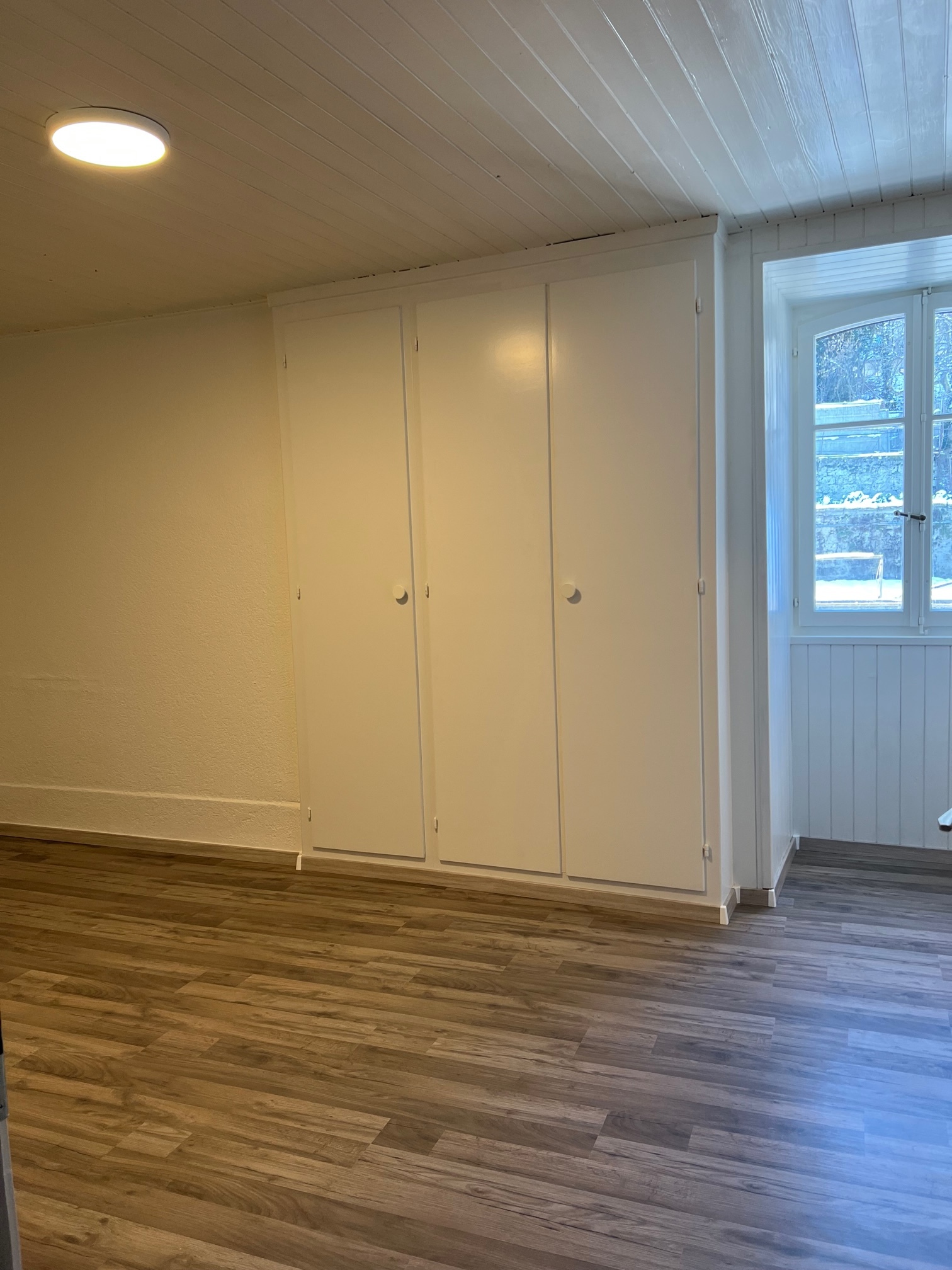 Heller Dachraum mit Einbauschrank und Fenster