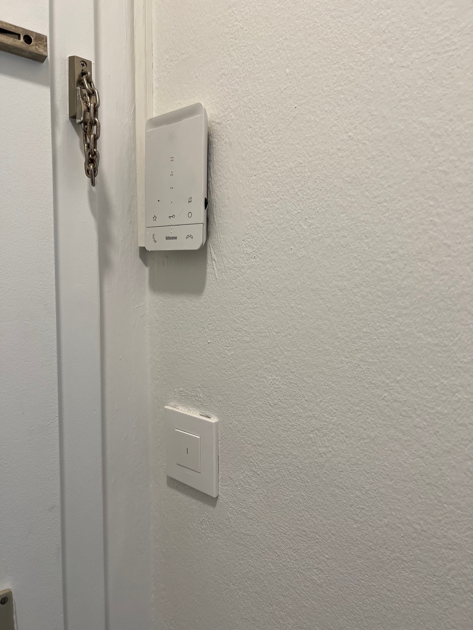 Innenansicht einer weißen Wand mit Gegensprechanlage und Lichtschalter