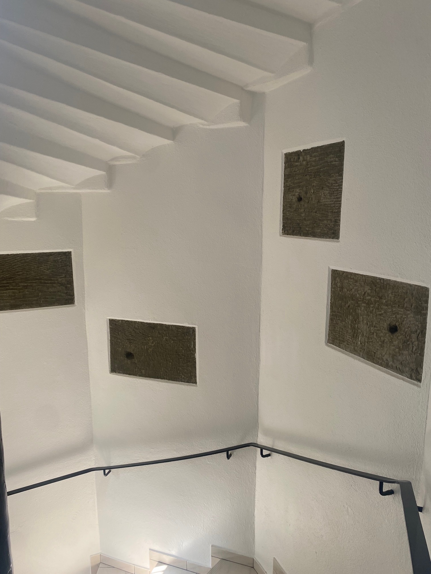 Treppenhaus mit weißem Putz und dunklen Wandnischen
