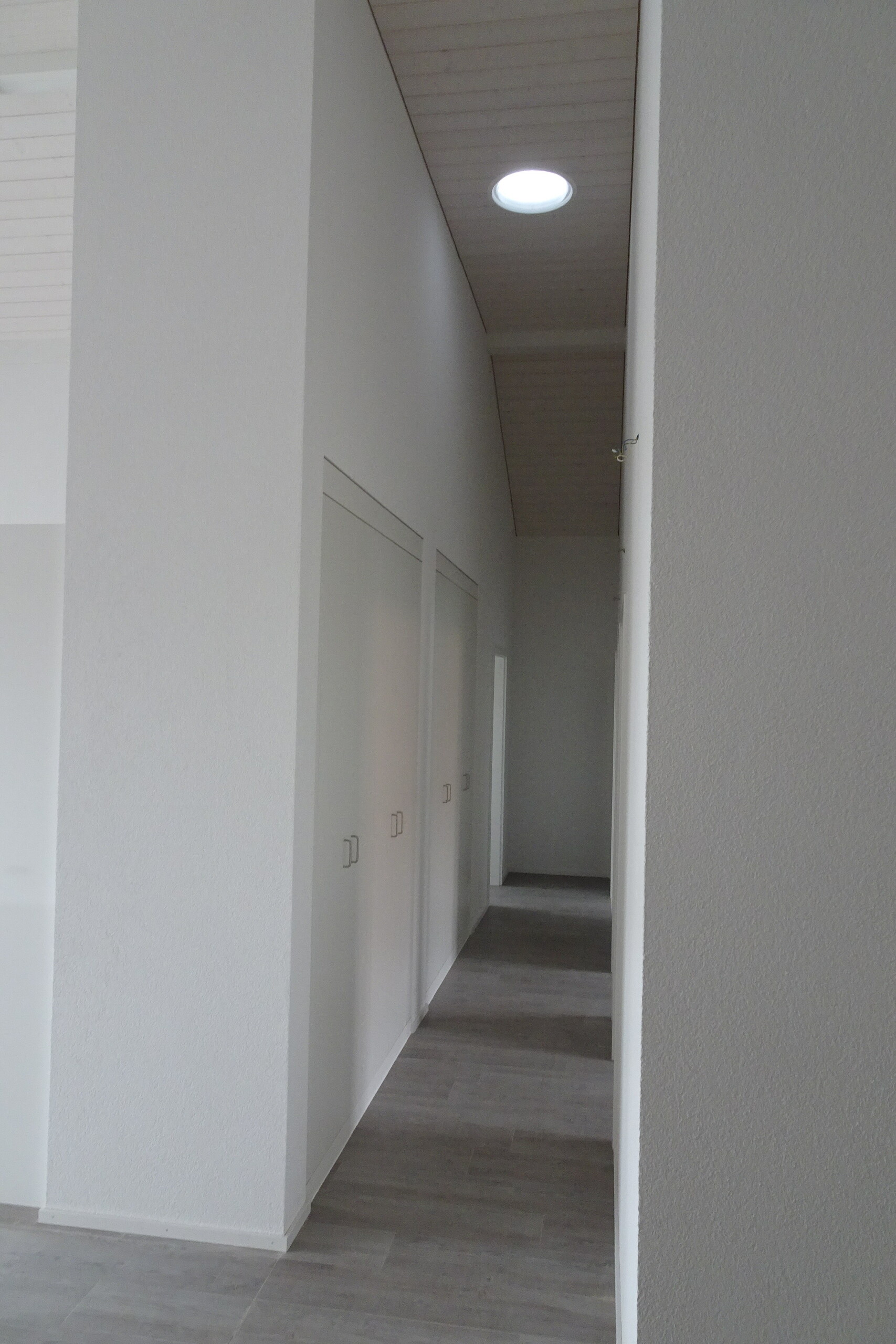 Flur mit weiß gestrichenen Wänden und Oberlicht