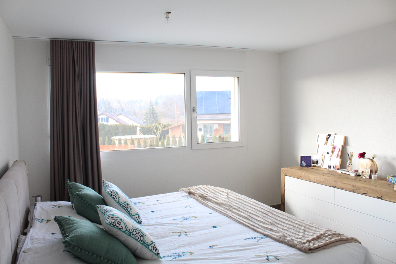 Helles Schlafzimmer mit Fenster und Kommode
