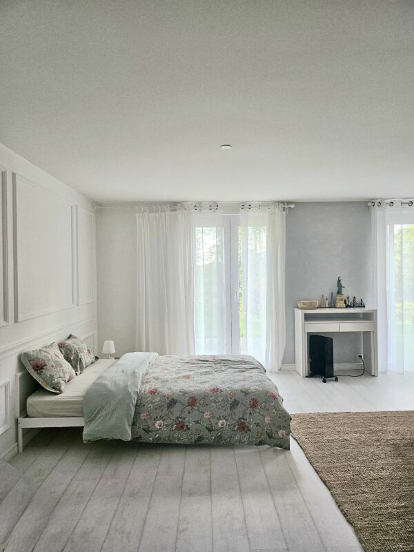 Helles, minimalistisches Schlafzimmer mit Bett und großem Fensterbereich