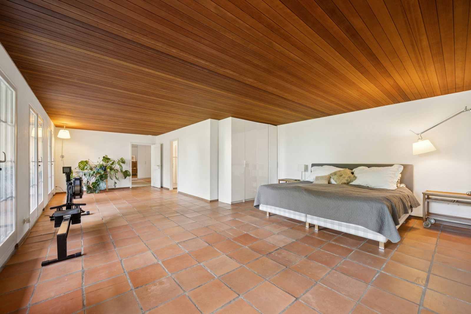 Großes Schlafzimmer mit Holzdecke und Terrakottaboden