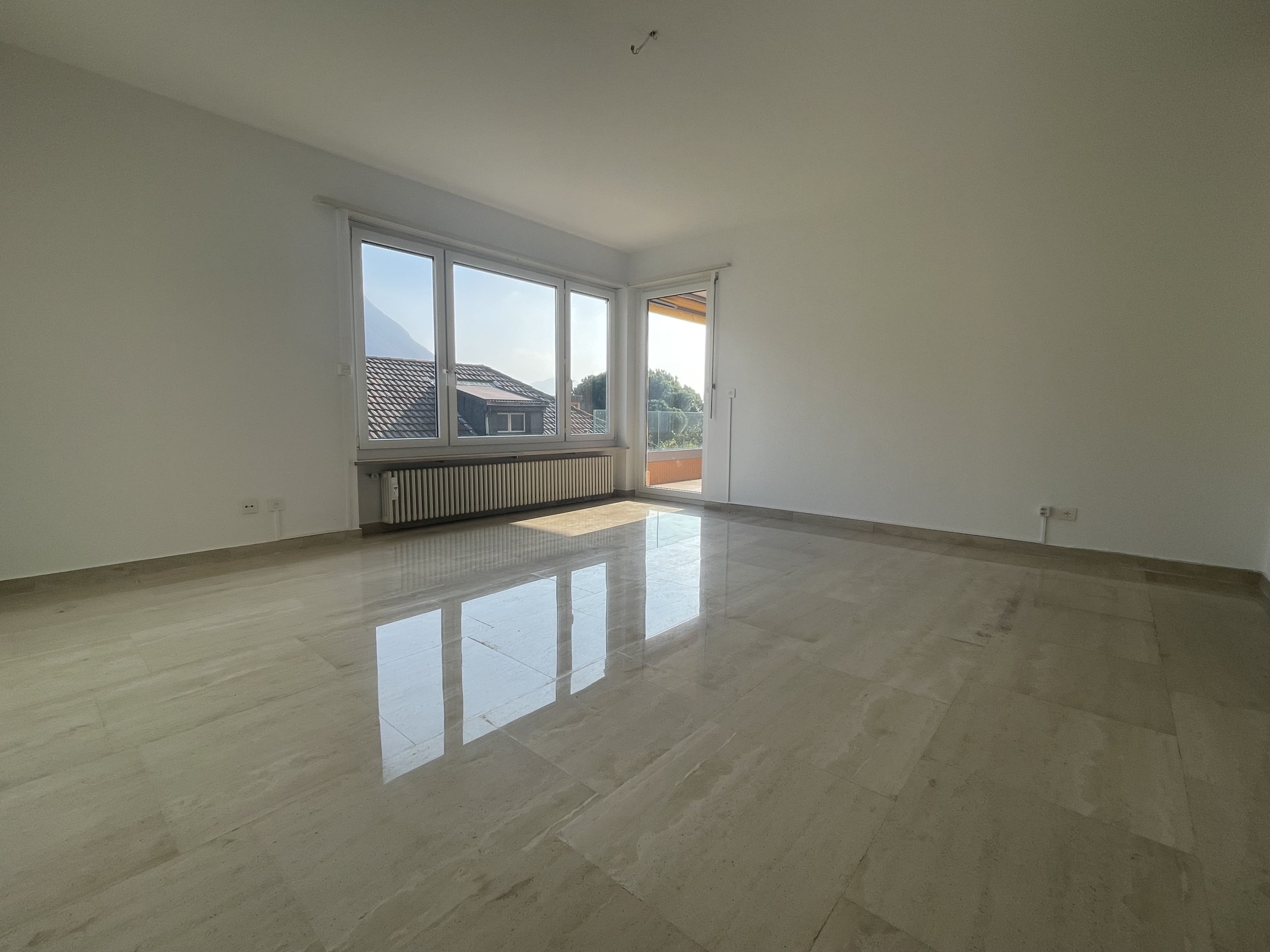 Heller leerer Wohnraum mit Balkon- und Bergblick