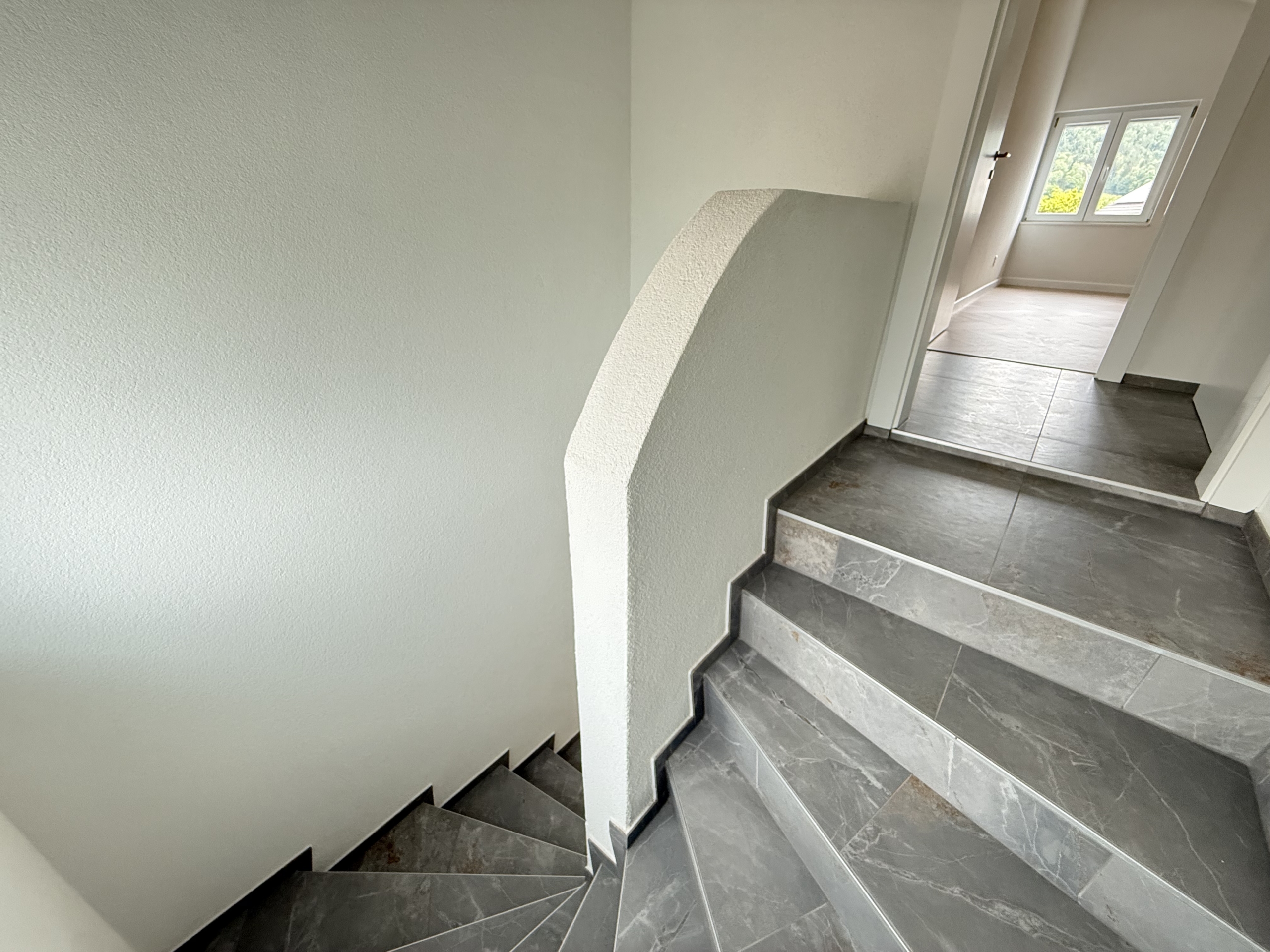 Treppenhaus mit Flur und Blick in einen hellen Raum
