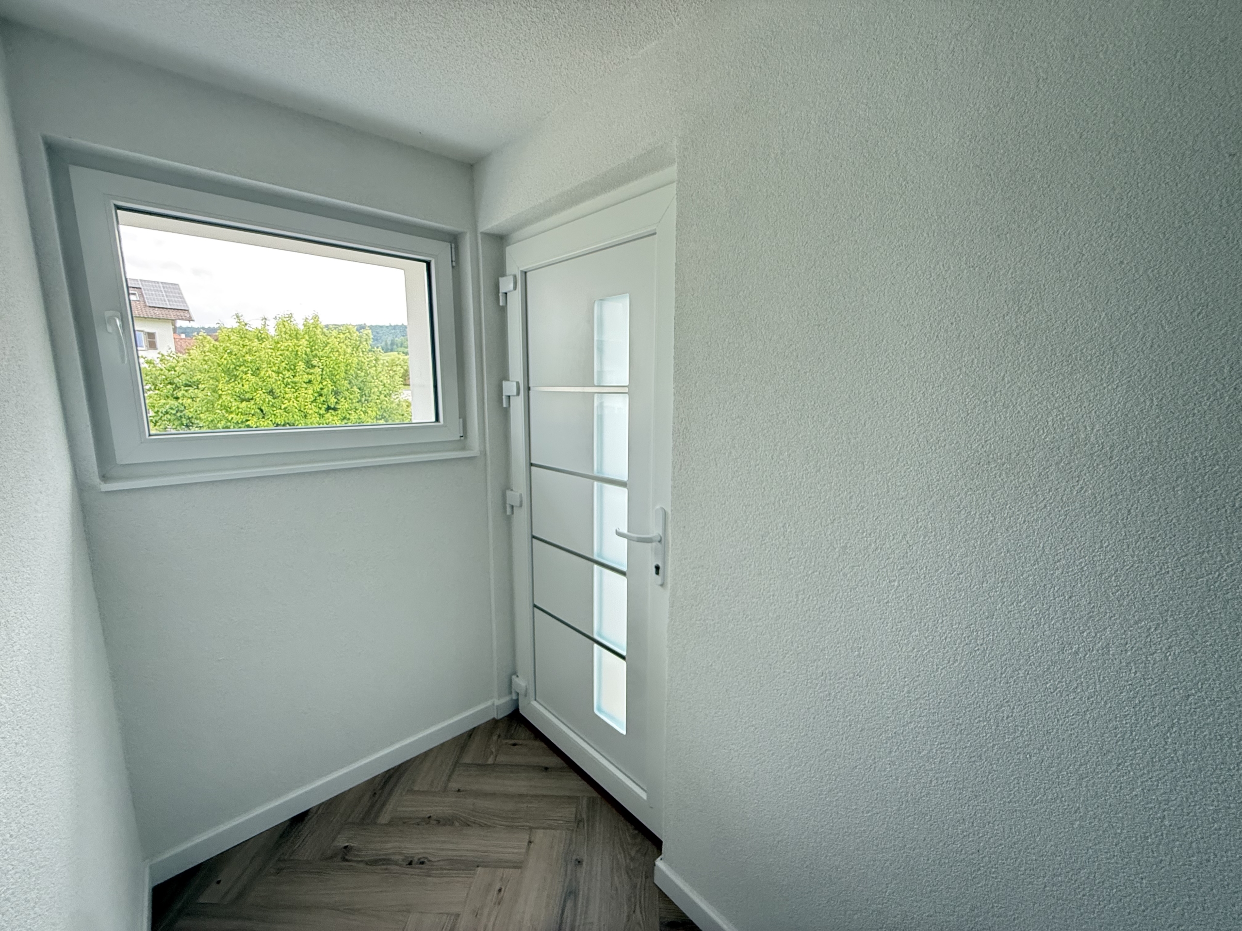 Heller Flur mit Fenster und weißer Tür