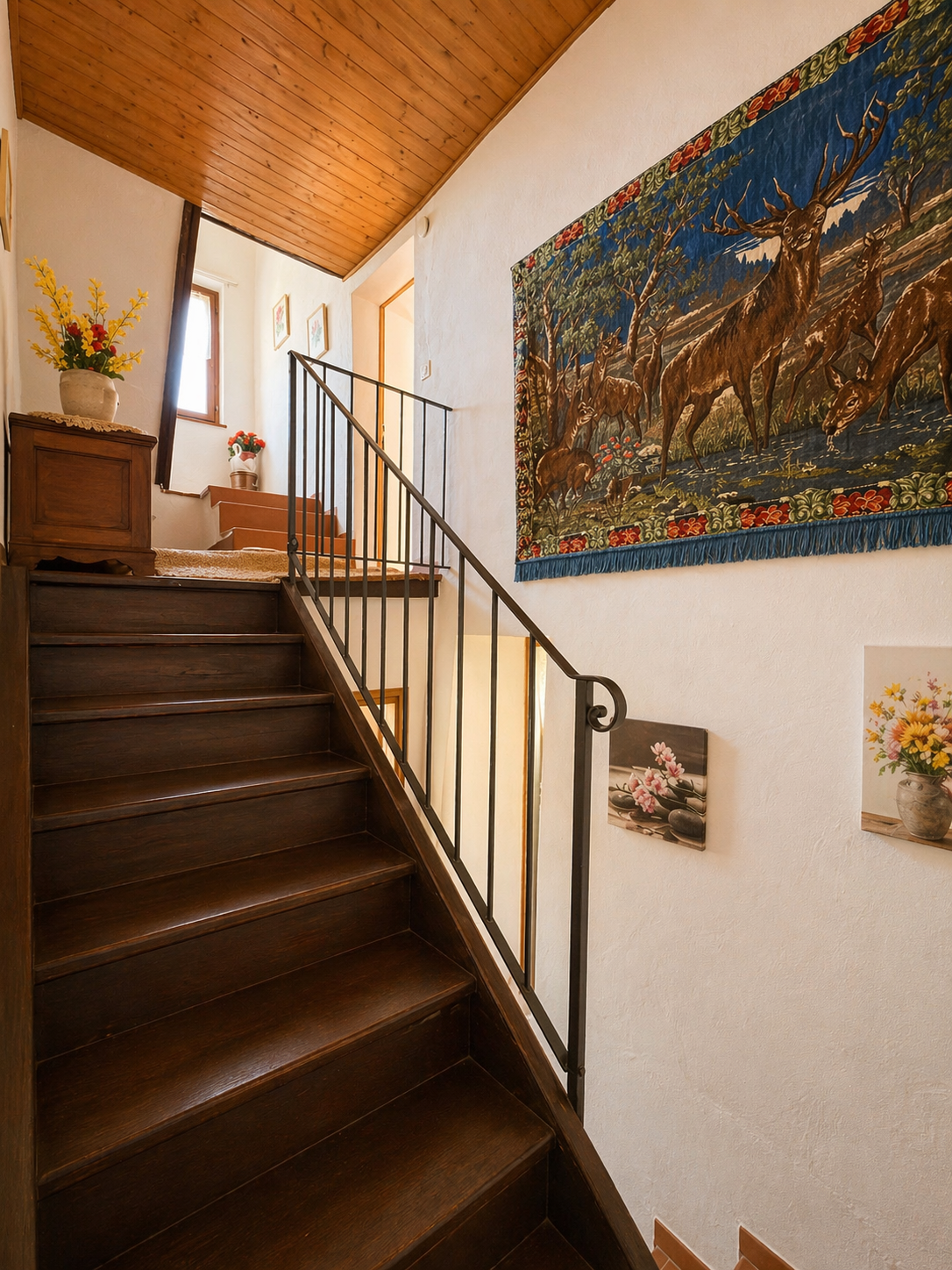 Treppenhaus mit Holzstufen und Wandteppich