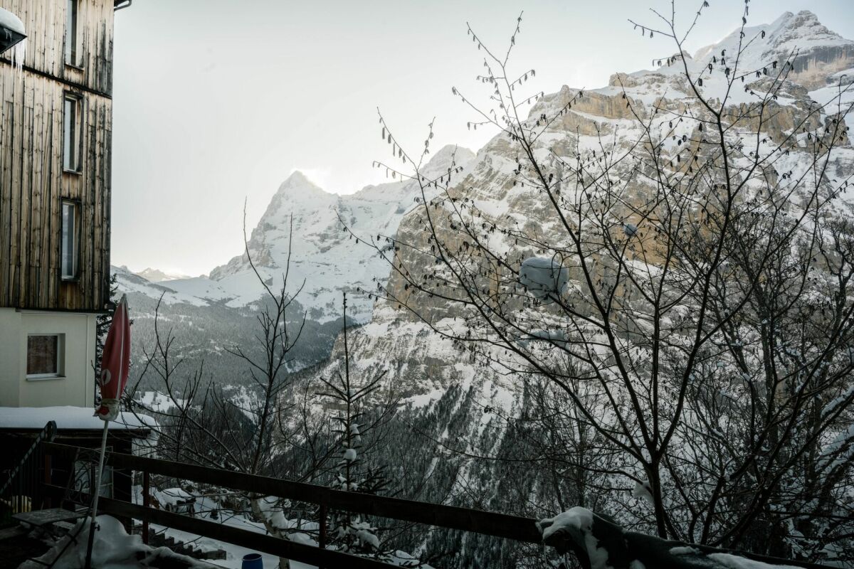 Schneebedeckter Berghang mit Gebäude und Talblick