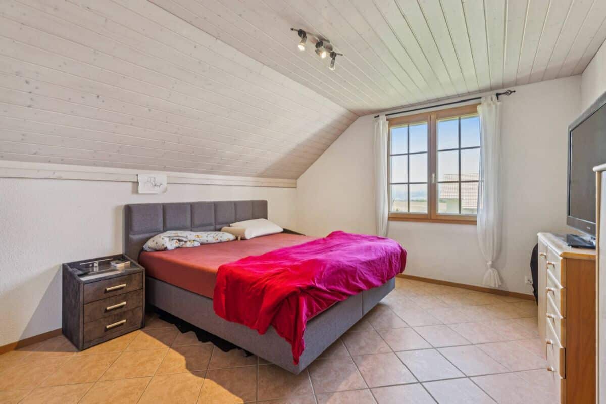 Dachgeschoss-Schlafzimmer mit Bett und Fenster