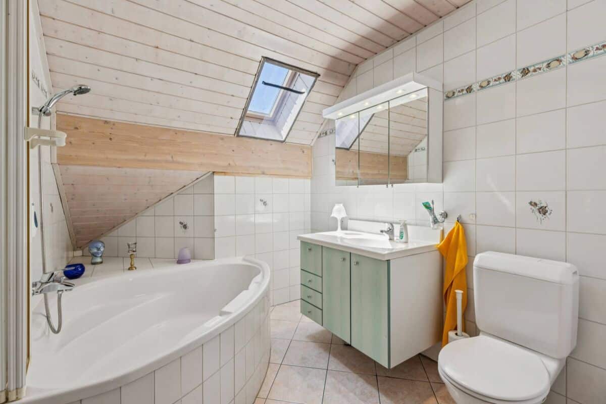 Dachgeschoss-Badezimmer mit Badewanne, Waschtisch und WC