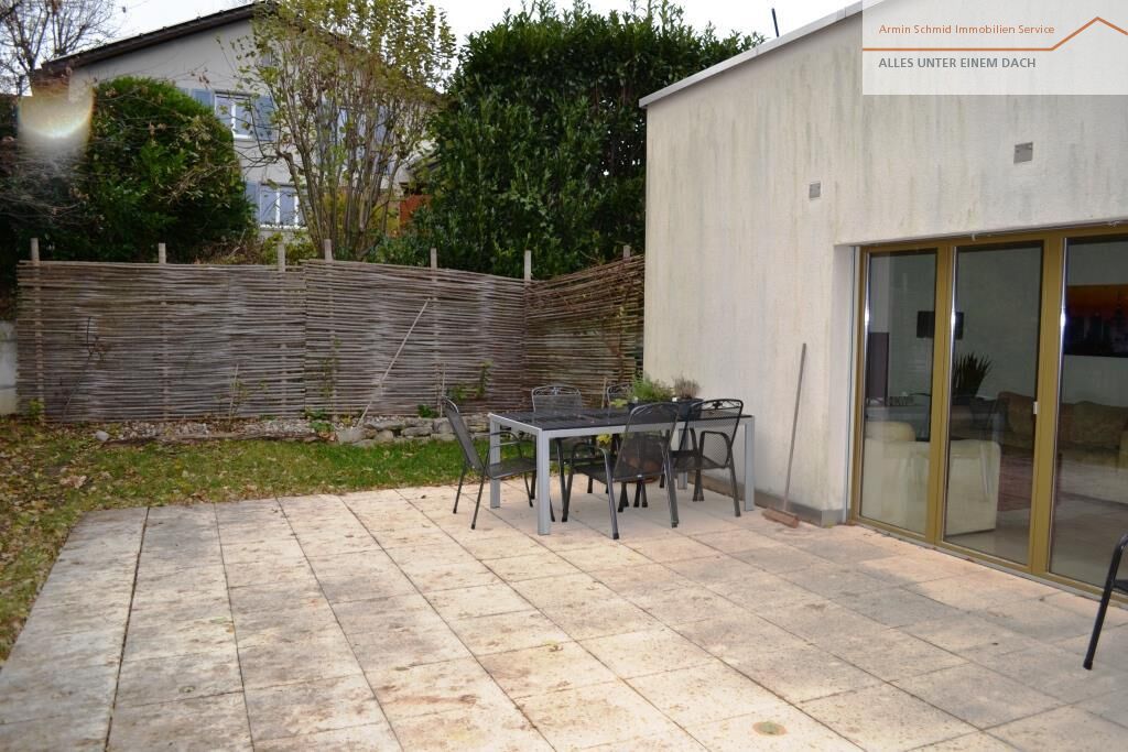 Terrasse mit Gartenmöbeln neben dem Haus