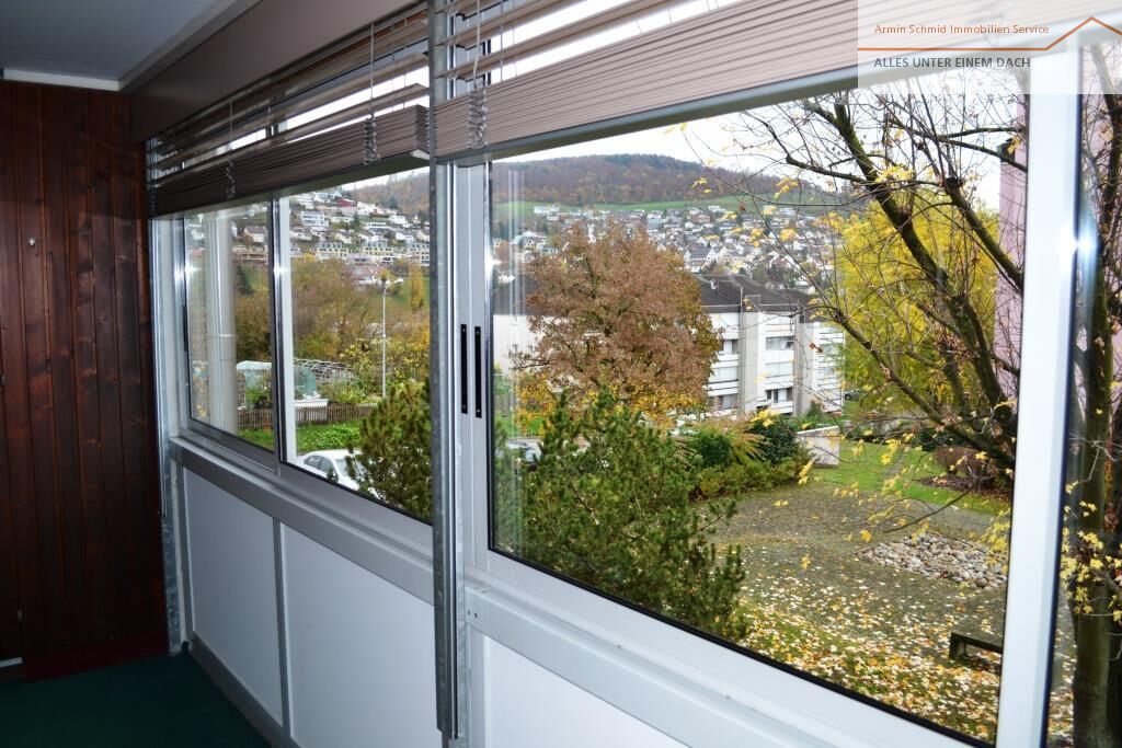 Verglaster Innenbereich mit Ausblick ins Grüne und auf Wohngebäude