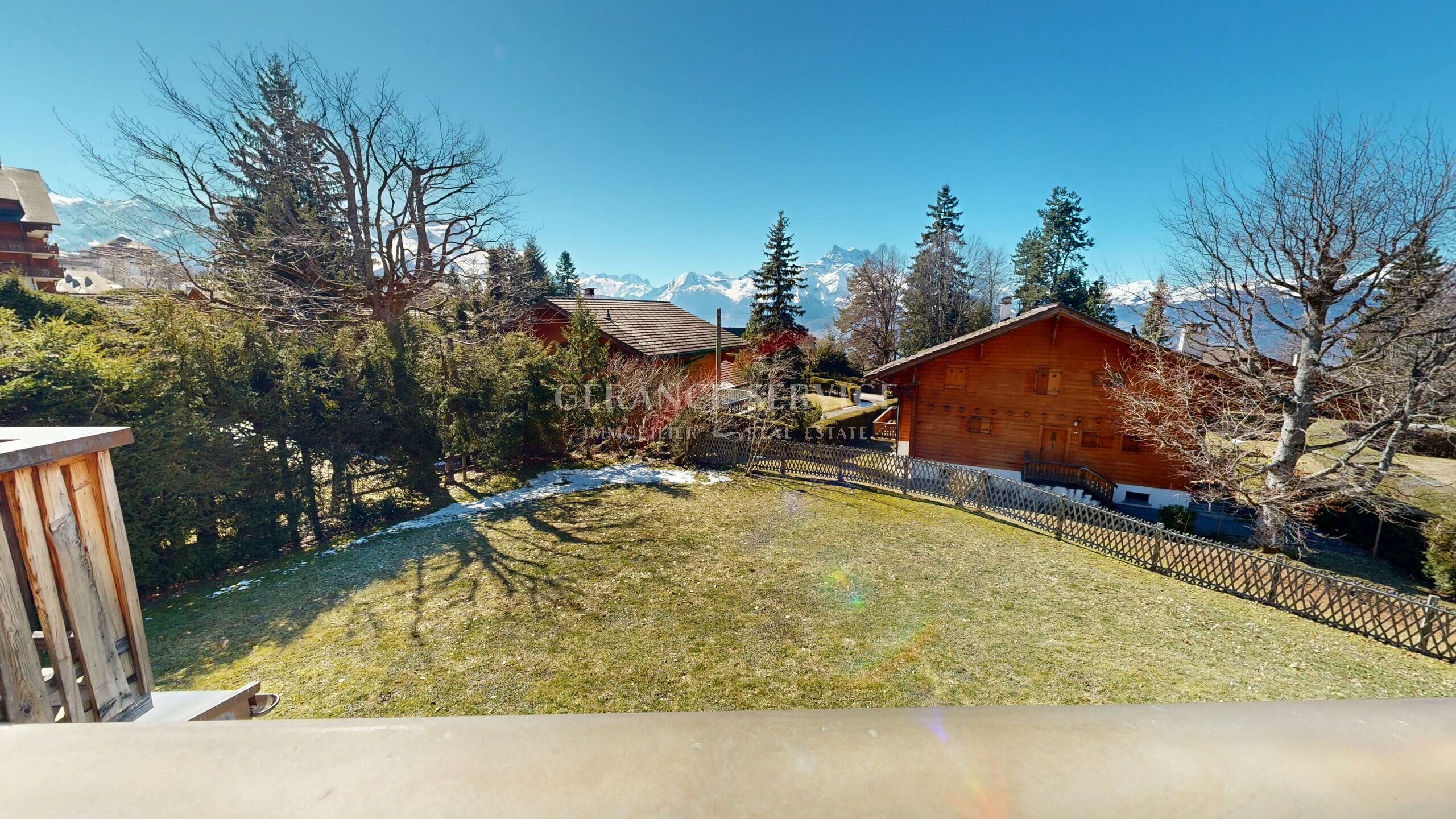 Alpenblick über Garten und Holzgebäude