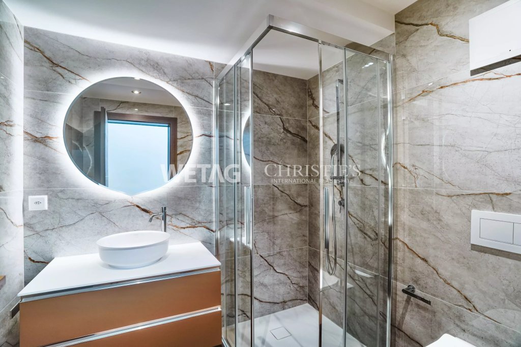 Modernes Badezimmer mit begehbarer Dusche und rundem Spiegel