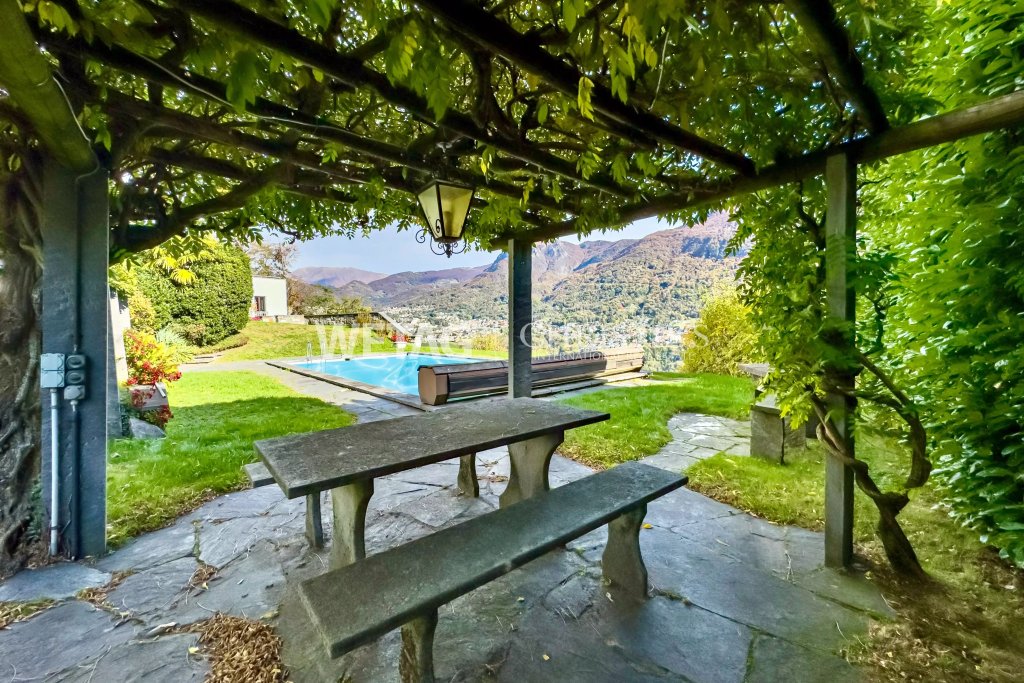 Überdachte Gartenterrasse mit Pool- und Bergblick
