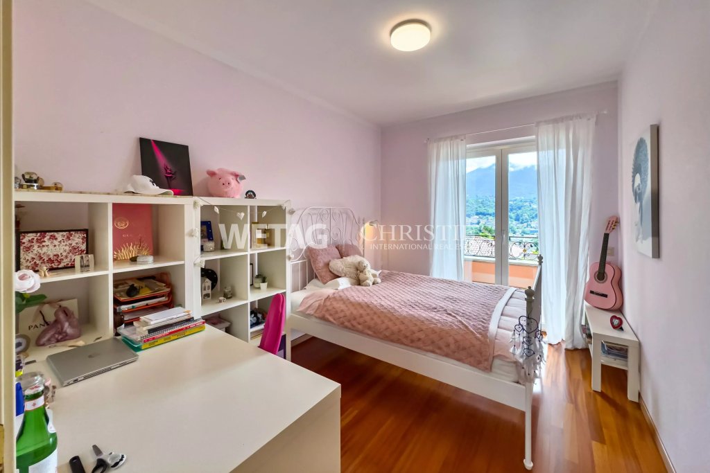Hell eingerichtetes Schlafzimmer mit Arbeitsplatz und Balkonblick