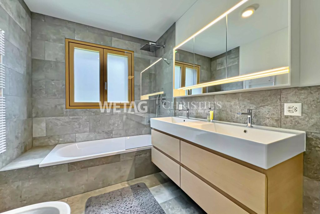 Modernes Badezimmer mit Natursteinoptik und beleuchtetem Spiegelschrank