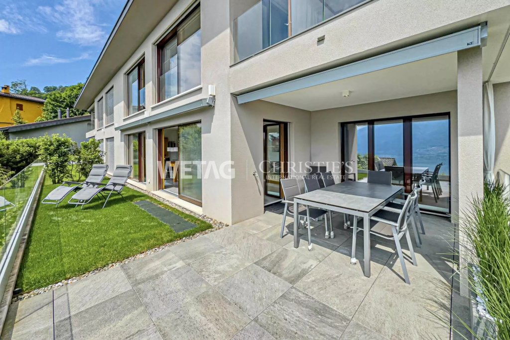 Moderne Terrasse mit Garten und großzügiger Glasfassade