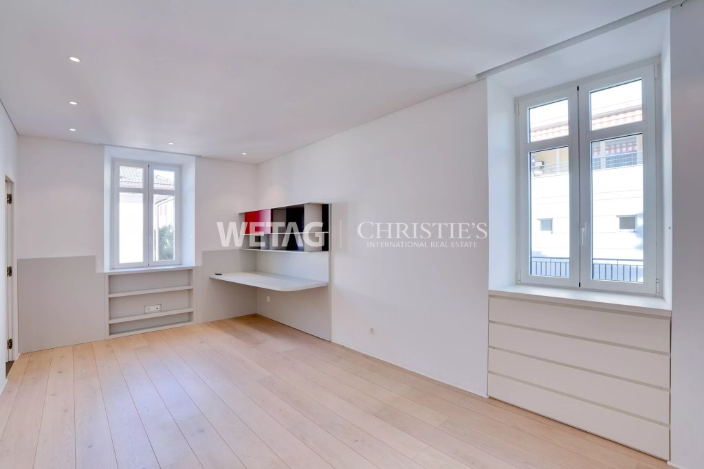 Helles, leeres Zimmer mit großen Fenstern und Einbaumöbeln