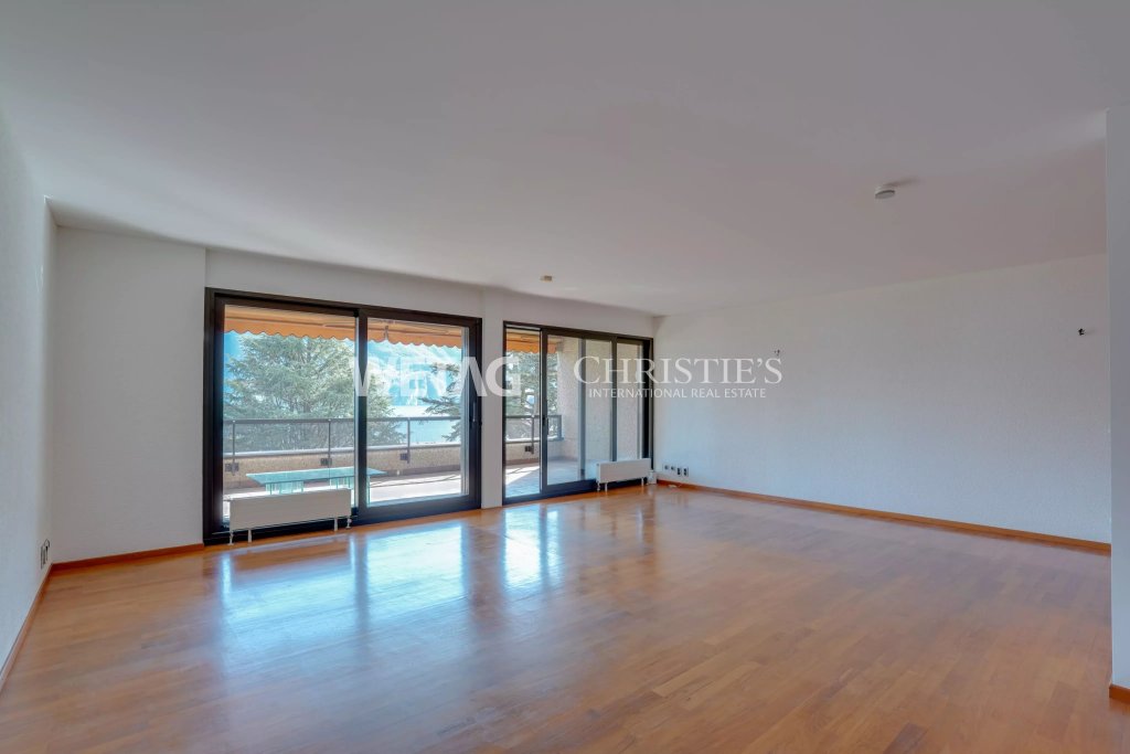 Leerer Wohnraum mit großer Fensterfront und Balkonblick