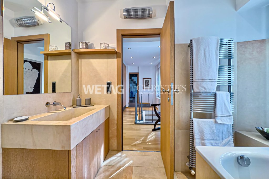 Badezimmer mit Natursteinwaschtisch und angrenzendem Flur