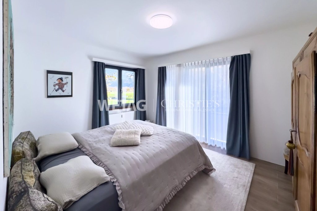 Helles Schlafzimmer mit großem Bett und Fensterfront