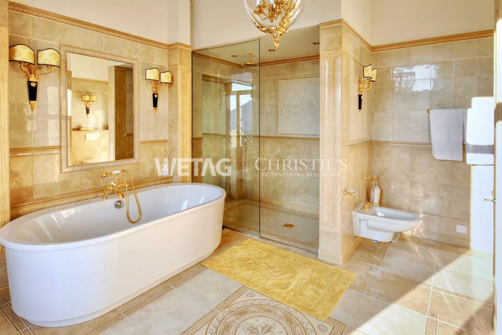 Luxuriöses Badezimmer mit Badewanne, Glasdusche und Goldakzenten