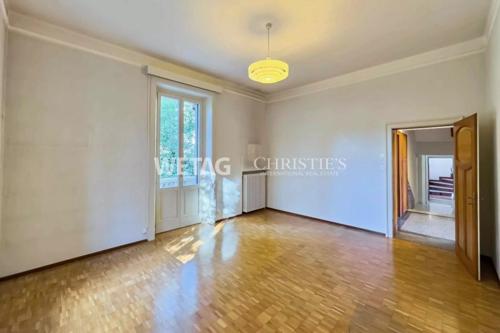 Leerer Altbau-Raum mit Parkett und Fenster