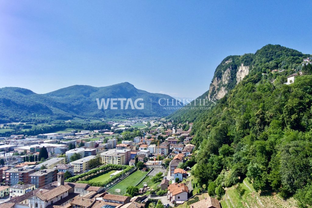 Panoramablick über eine Stadt im Tal mit Bergen und Felswand