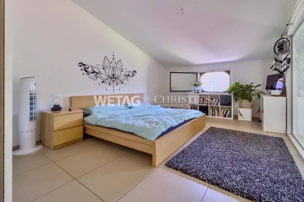 Helles Schlafzimmer mit großem Bett und Fensterfront