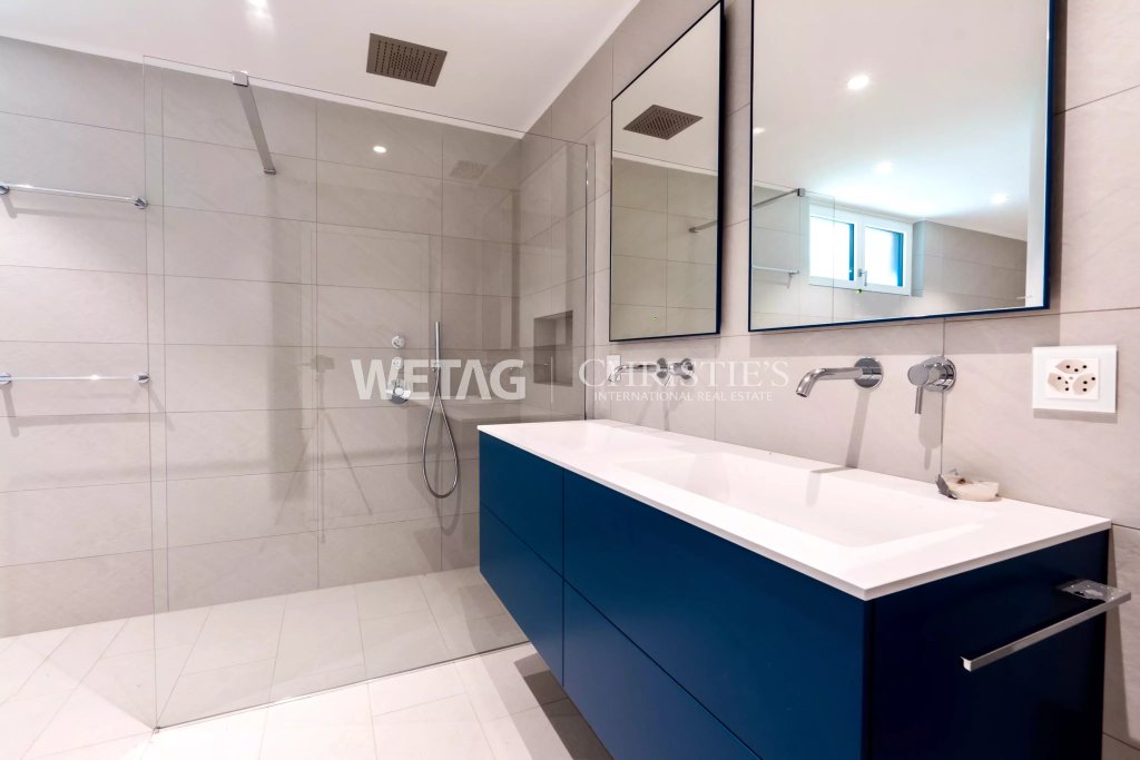 Modernes Badezimmer mit Glasdusche und blauem Waschtischunterschrank