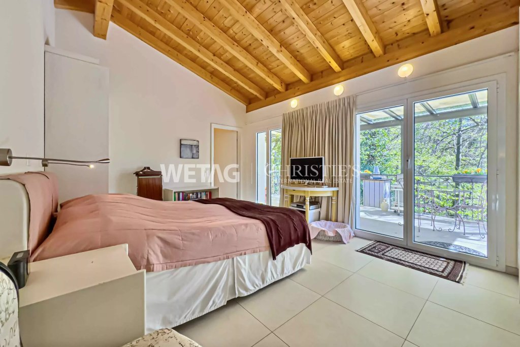 Helles Schlafzimmer mit Holzbalkendecke und Balkonblick