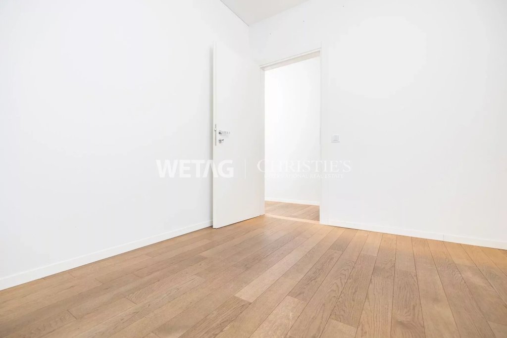 Heller leerer Raum mit Holzboden und geöffneter Tür