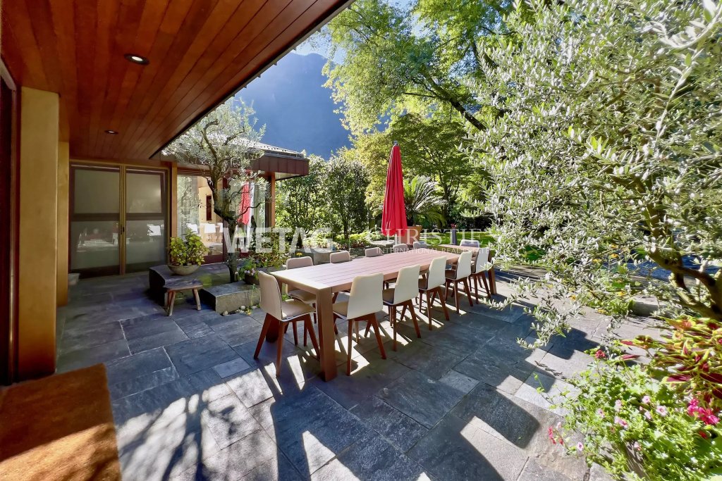 Gedeckte Terrasse mit großem Esstisch im Garten