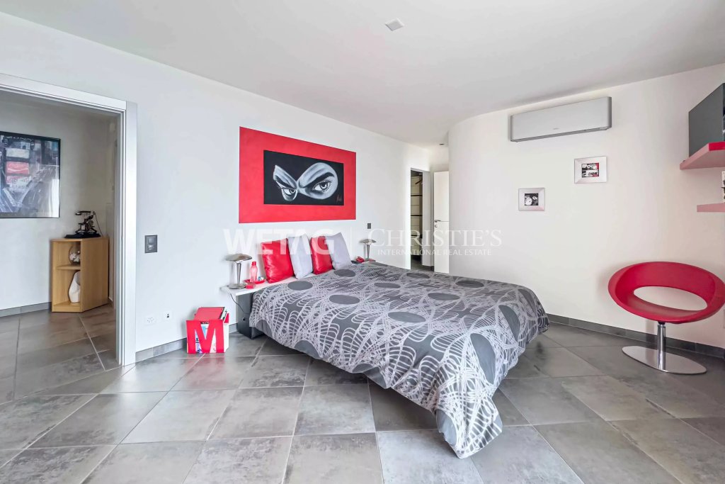 Modernes Schlafzimmer mit grauem Fliesenboden und roten Akzenten