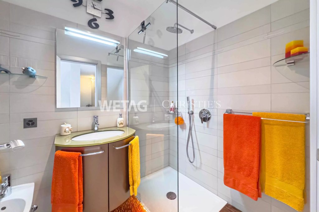 Modernes Badezimmer mit Glasdusche und farbigen Handtüchern
