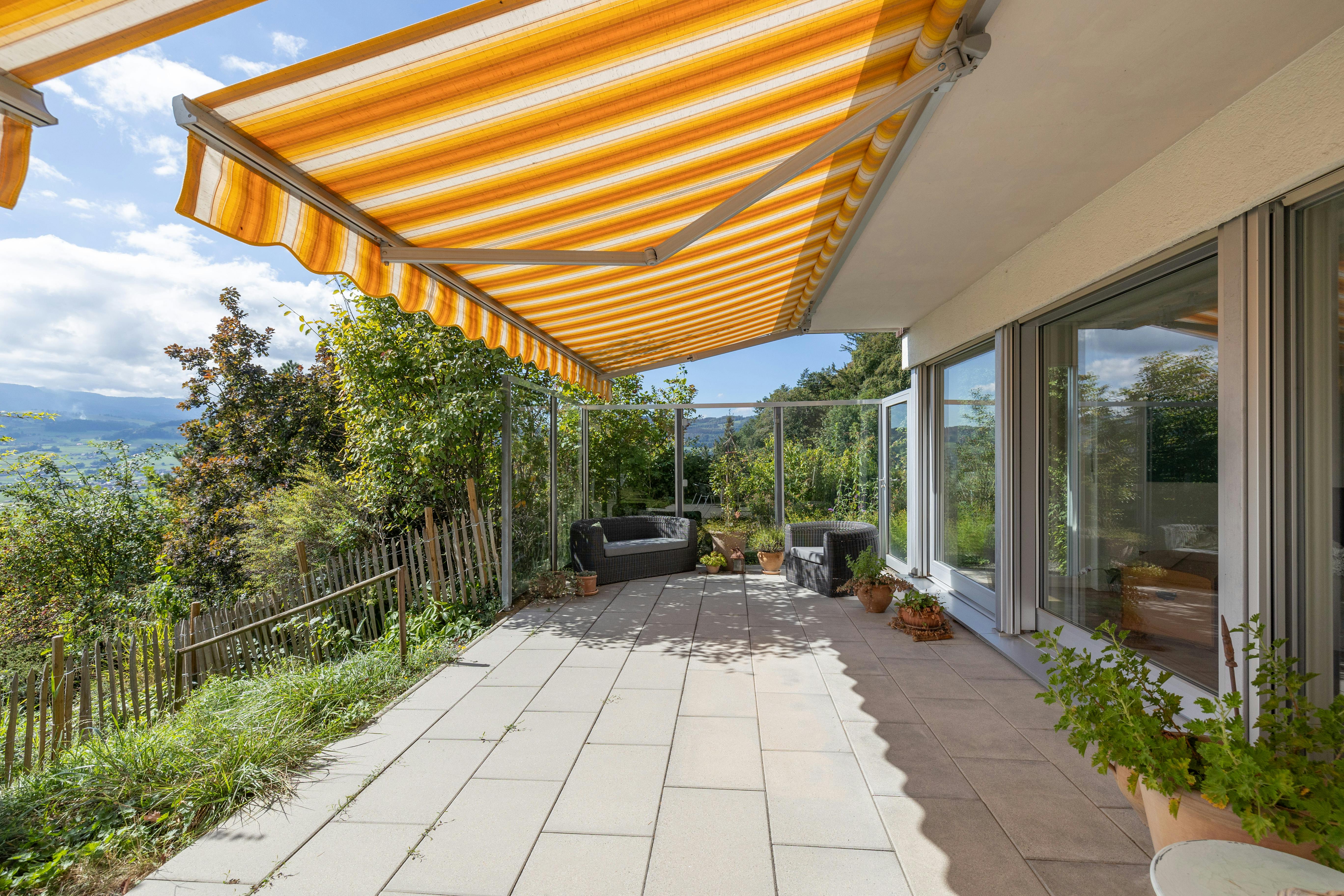Überdachte Terrasse mit Markise und Gartenblick