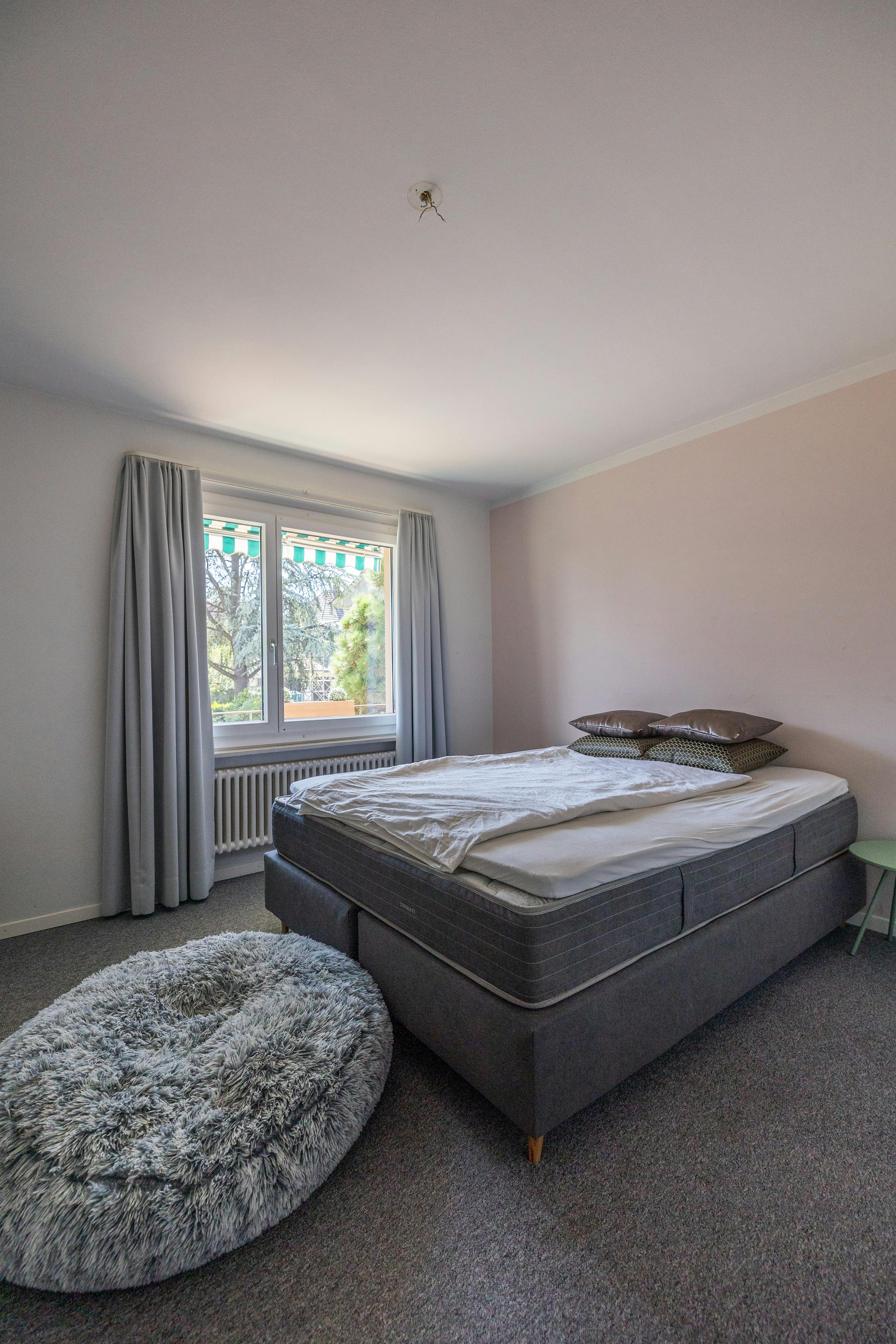 Schlafzimmer mit großem Fenster und Doppelbett