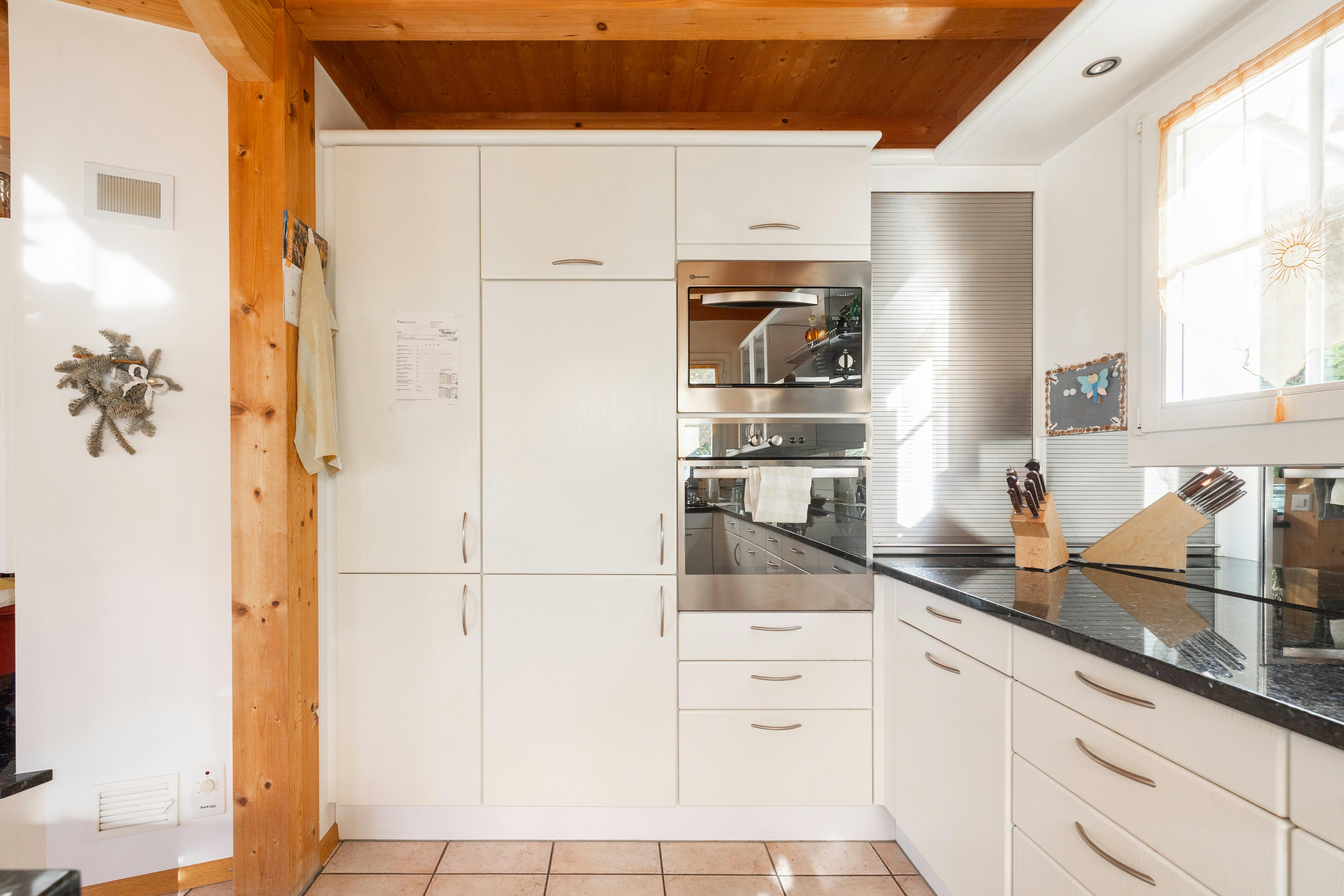 Helle Küche mit weißen Schränken und Holzdecke