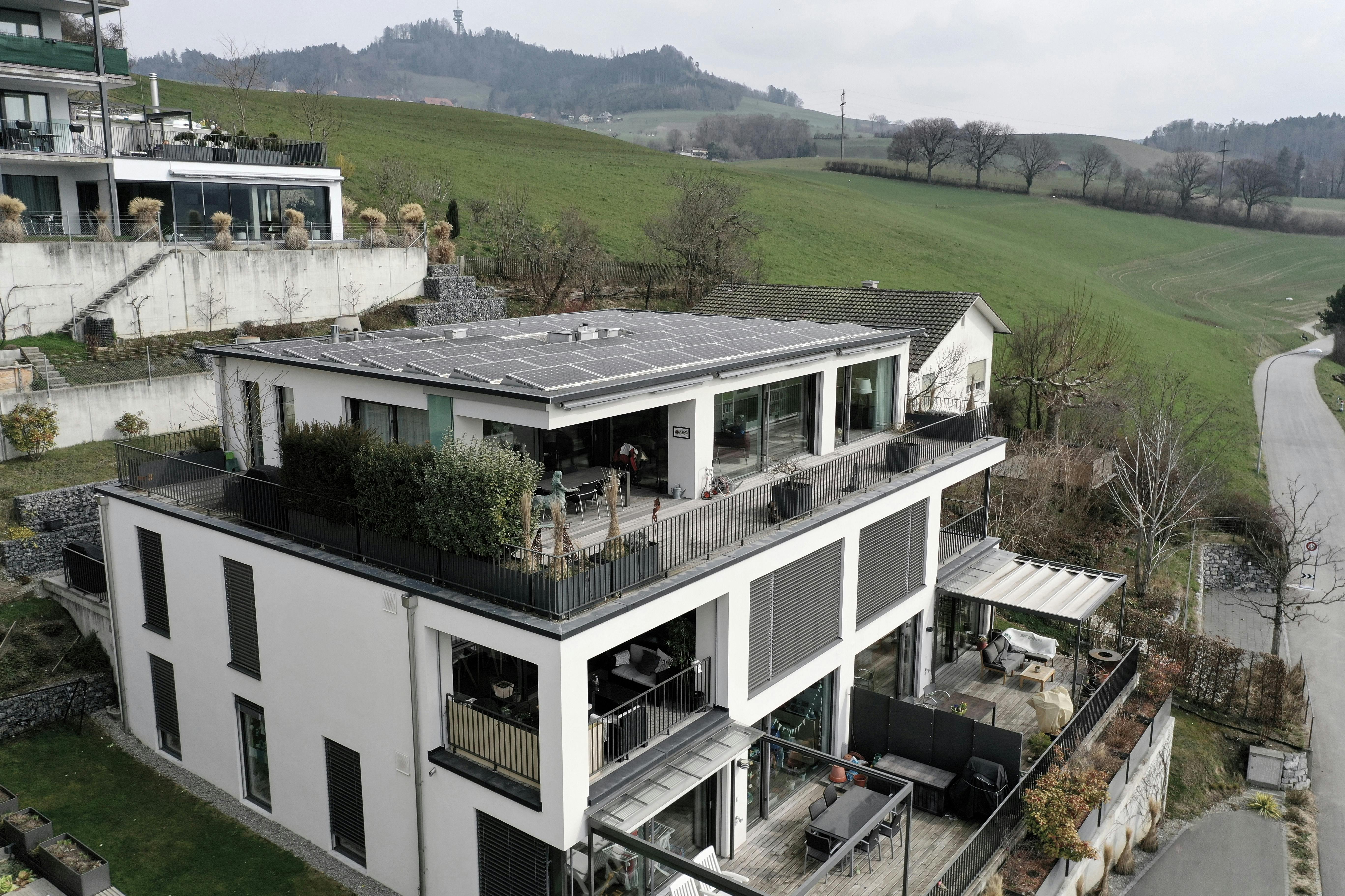Moderne Mehrfamilien-/Terrassenhausansicht mit Solardach und Blick ins Grüne