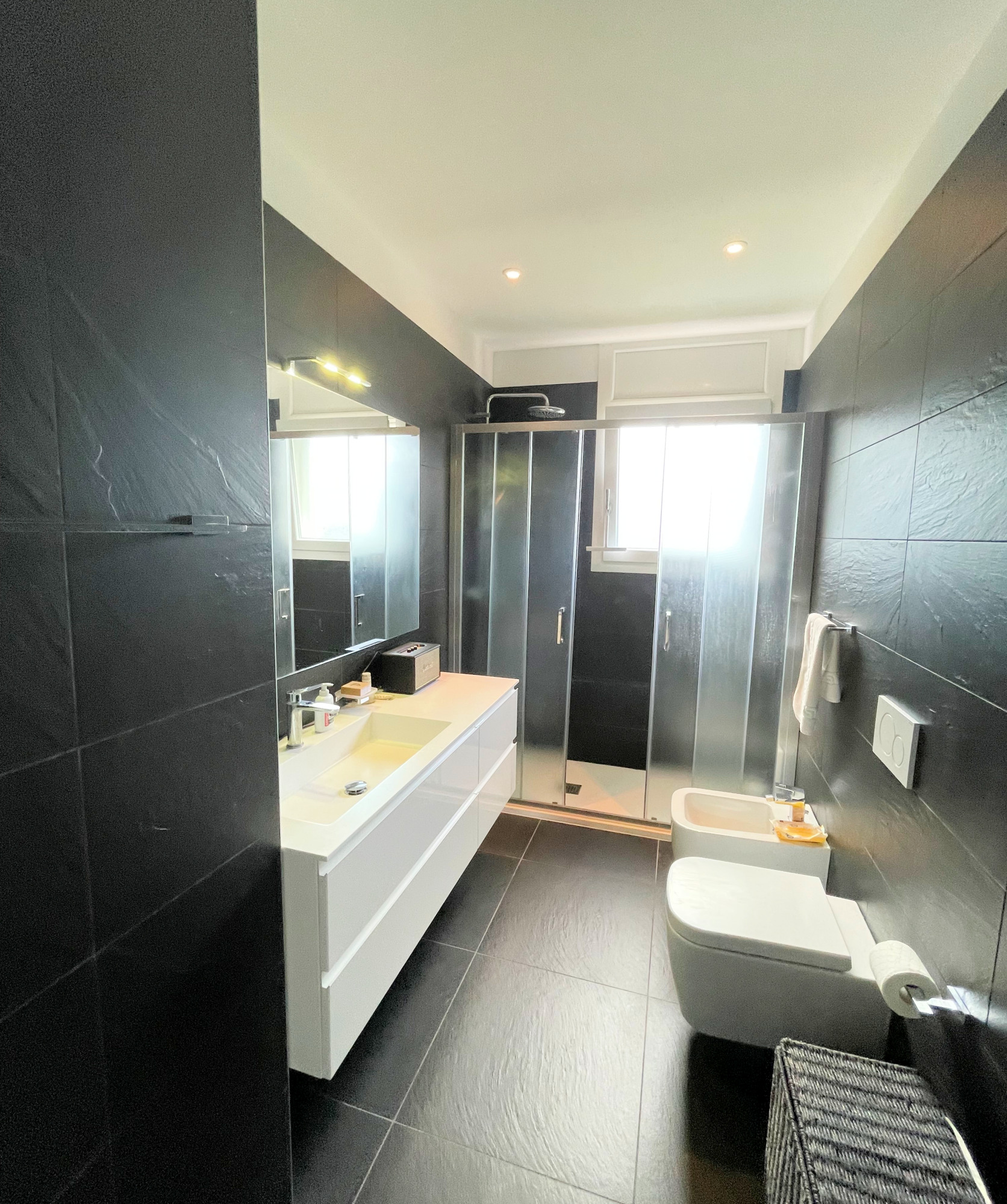 Modernes Badezimmer mit dunklen Fliesen und Doppelwaschtisch