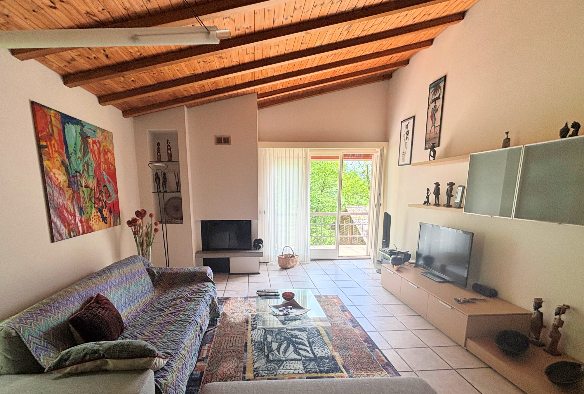 Helles Wohnzimmer mit sichtbaren Holzbalken und Balkonblick