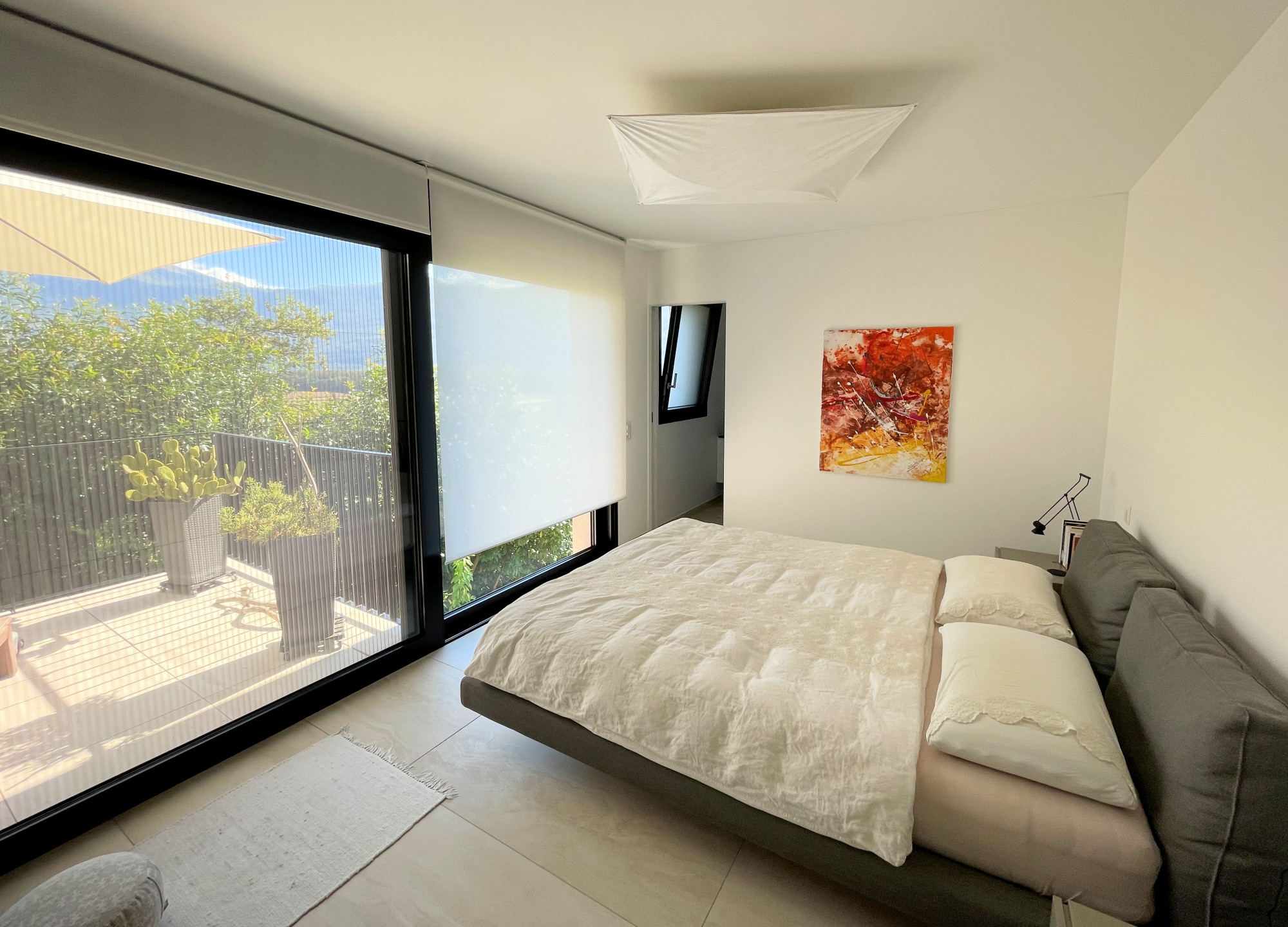 Modernes Schlafzimmer mit großem Fenster und Gartenblick