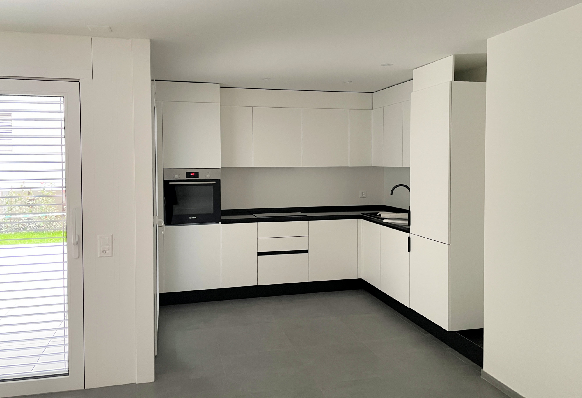 Moderne weiße Küche mit dunkler Arbeitsplatte