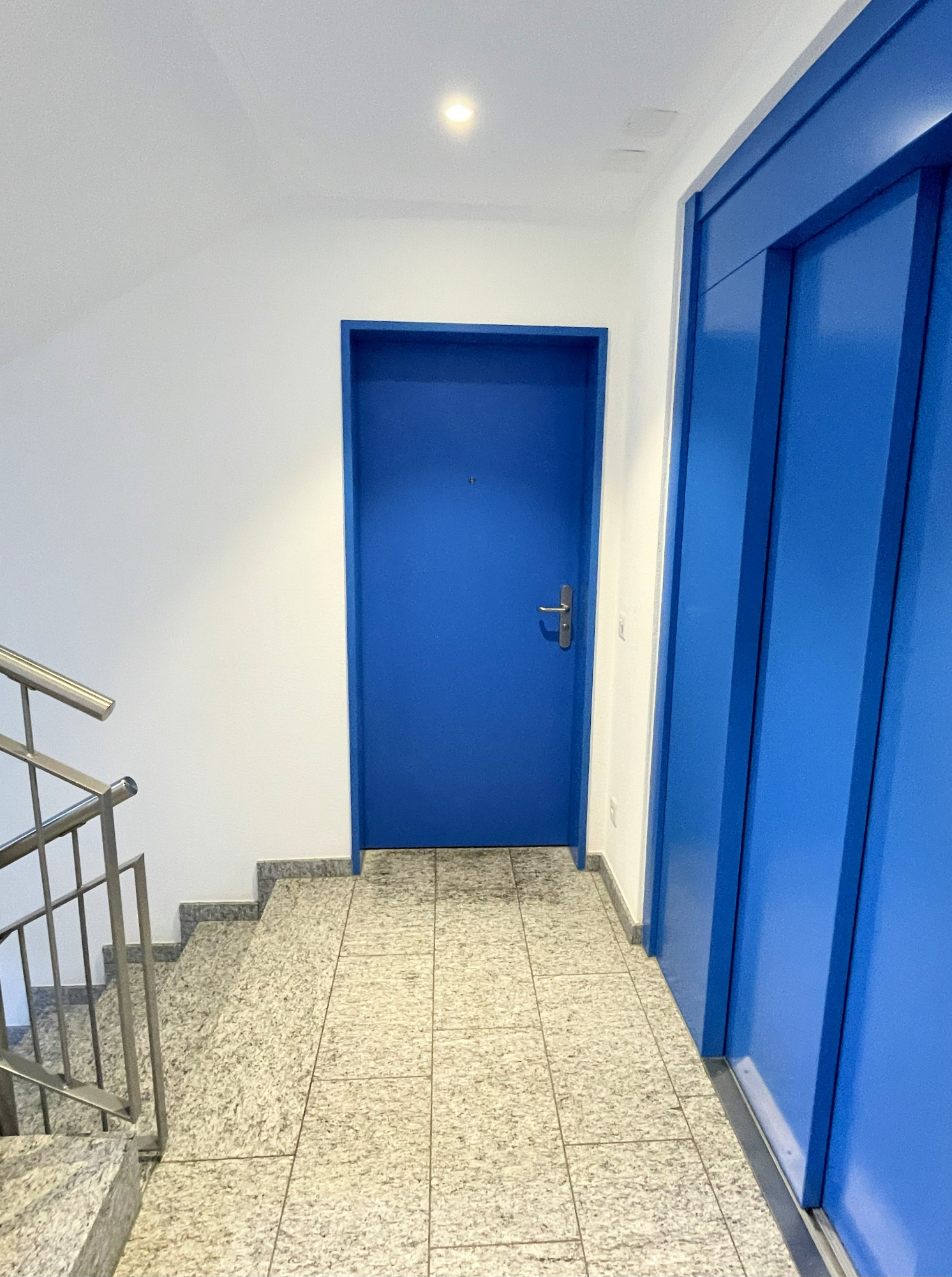 Treppenhaus mit blauer Wohnungstür