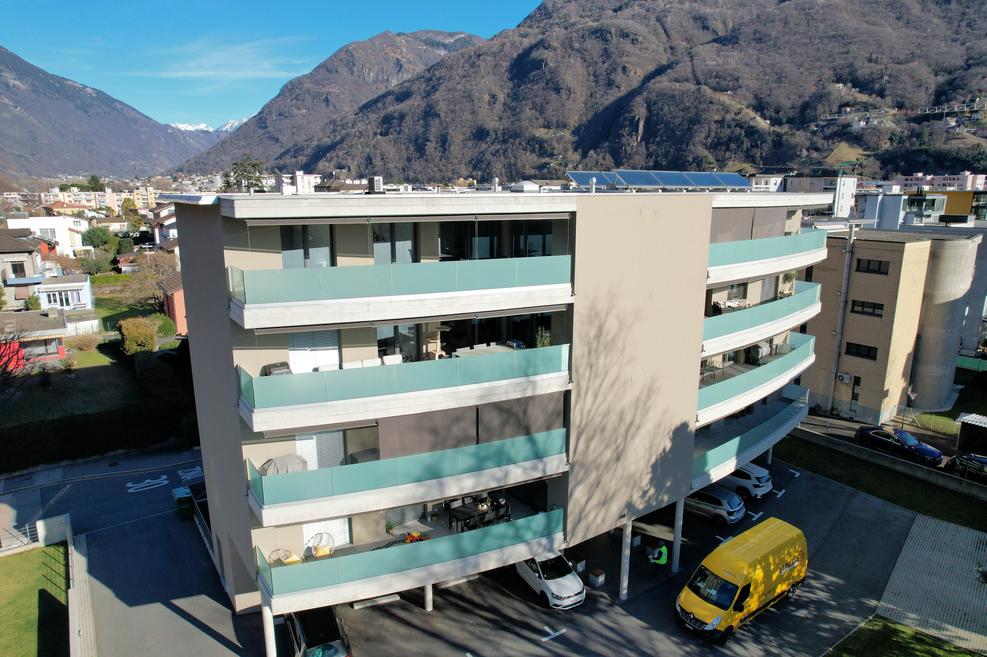 Modernes Mehrfamilienhaus mit Balkonen vor Bergkulisse